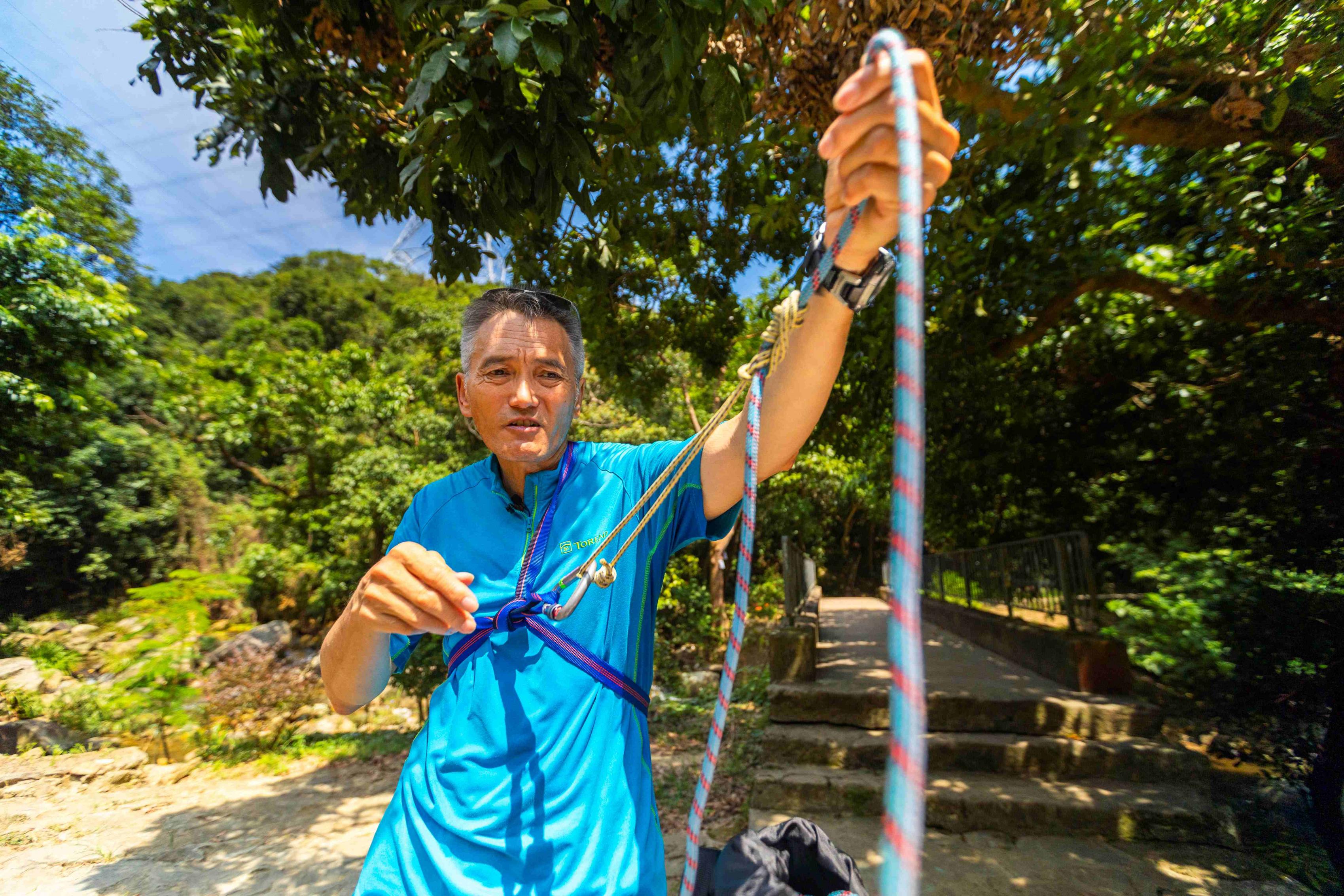 他示範如何使用繩索系統，這些都是從山藝課程中學到的安全技巧。